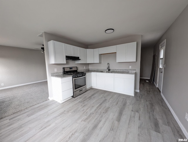 kitchen with light stone countertops, stainless steel range with gas cooktop, sink, and white cabinets