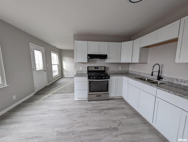 kitchen with white cabinetry, sink, light stone counters, and stainless steel gas range oven