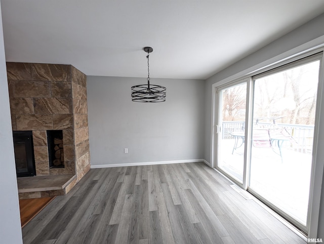 interior space with a stone fireplace, hardwood / wood-style floors, and a notable chandelier