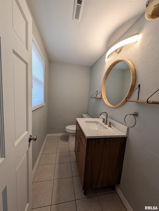 bathroom with tile patterned flooring, vanity, toilet, and a textured ceiling