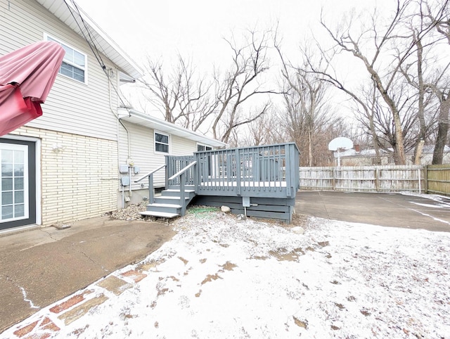 snow covered back of property with a wooden deck