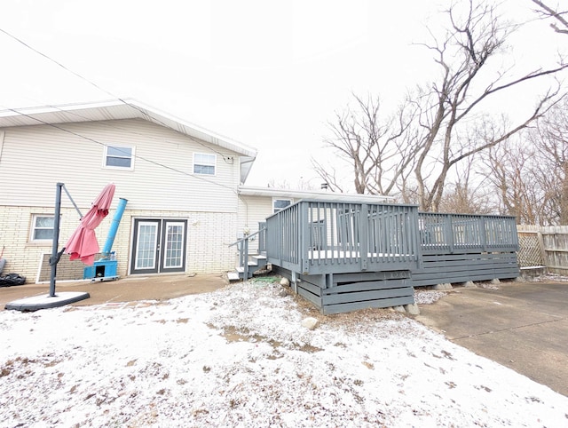 snow covered rear of property featuring a deck