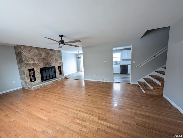 unfurnished living room featuring ceiling fan, light hardwood / wood-style floors, sink, and a fireplace