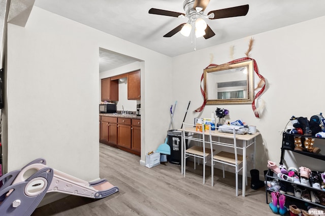 interior space with ceiling fan, sink, and light wood-type flooring