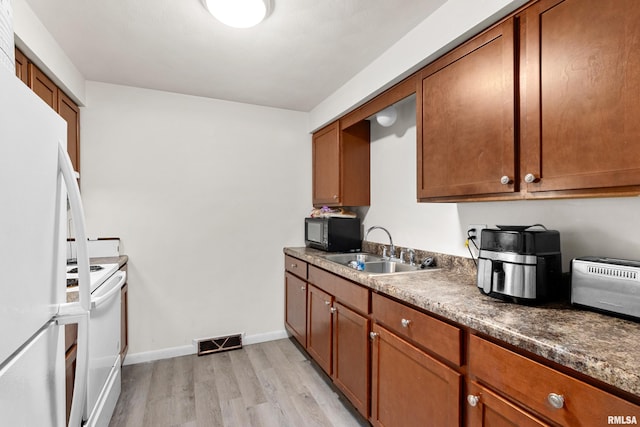 kitchen featuring light wood-type flooring, white appliances, sink, and dark stone counters