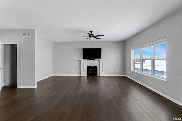 unfurnished living room with a brick fireplace, dark hardwood / wood-style flooring, and ceiling fan