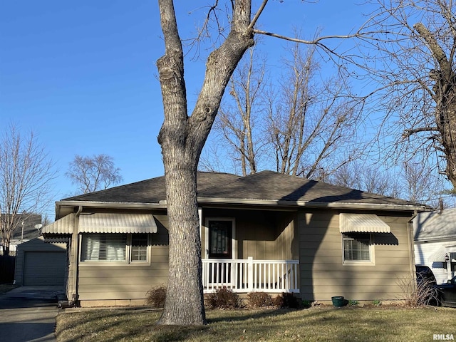 view of front of house featuring a front yard, covered porch, a garage, and an outbuilding