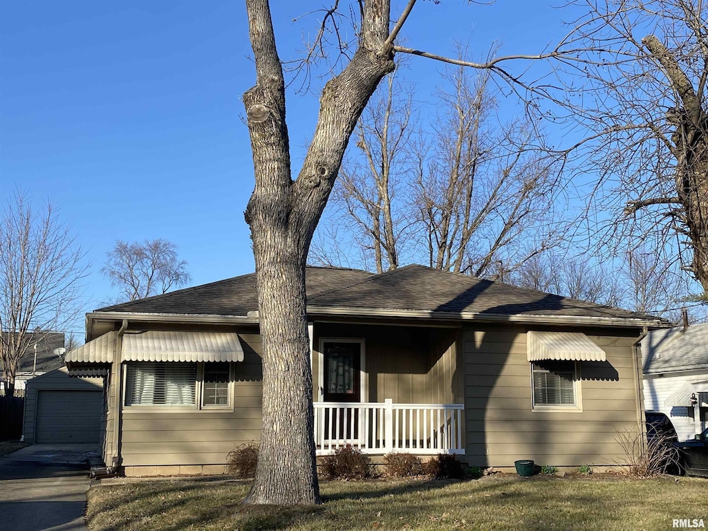 view of front of house featuring a front yard, covered porch, a garage, and an outbuilding