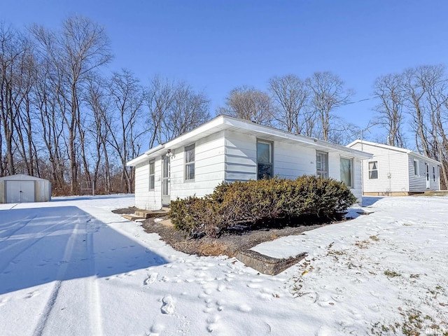 view of snowy exterior featuring a storage shed