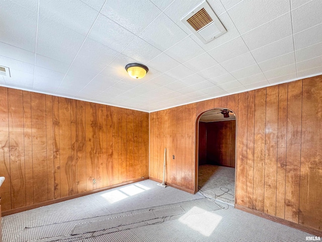 carpeted empty room featuring wooden walls