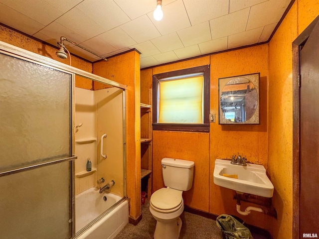 full bathroom with sink, toilet, combined bath / shower with glass door, and wood walls