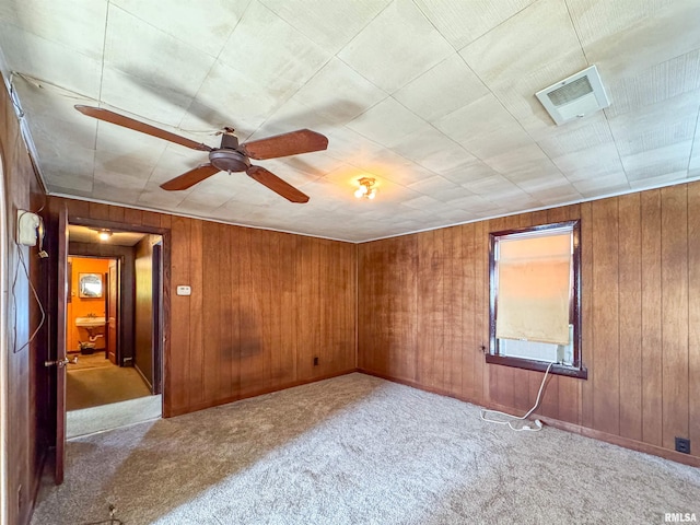 unfurnished room featuring ceiling fan, wooden walls, and light carpet