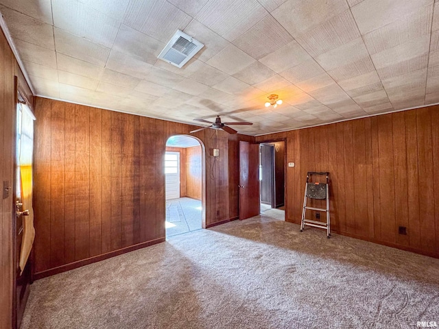 carpeted spare room with wooden walls and ceiling fan