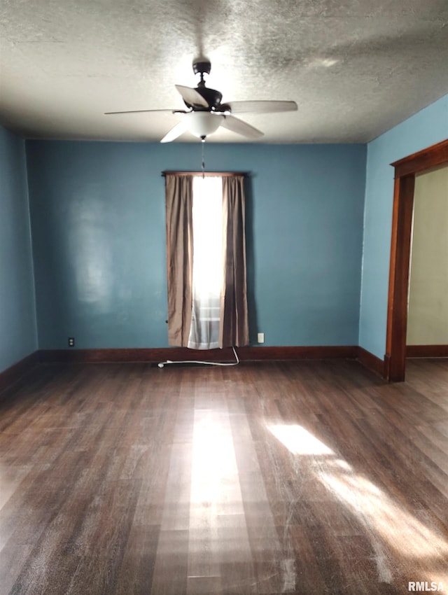 empty room featuring a textured ceiling, wood finished floors, baseboards, and ceiling fan