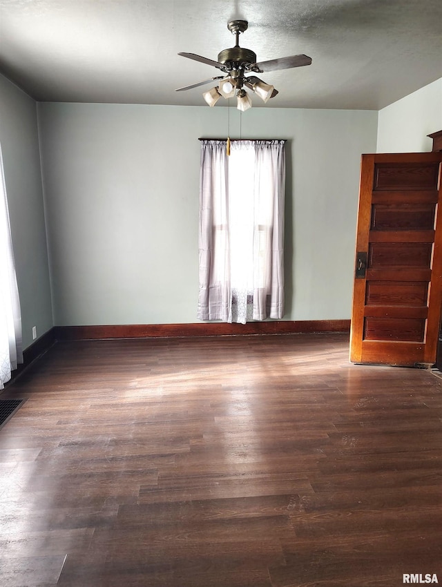 spare room featuring dark wood-style floors, baseboards, and ceiling fan