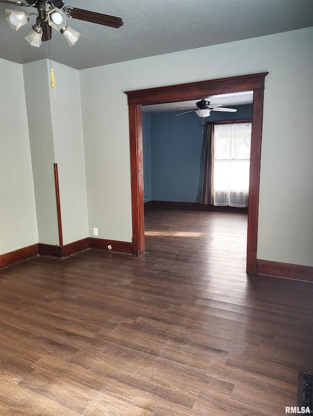 spare room featuring baseboards, wood finished floors, and a ceiling fan