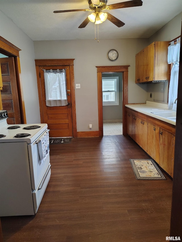 kitchen featuring brown cabinets, dark wood-type flooring, a sink, white electric stove, and ceiling fan