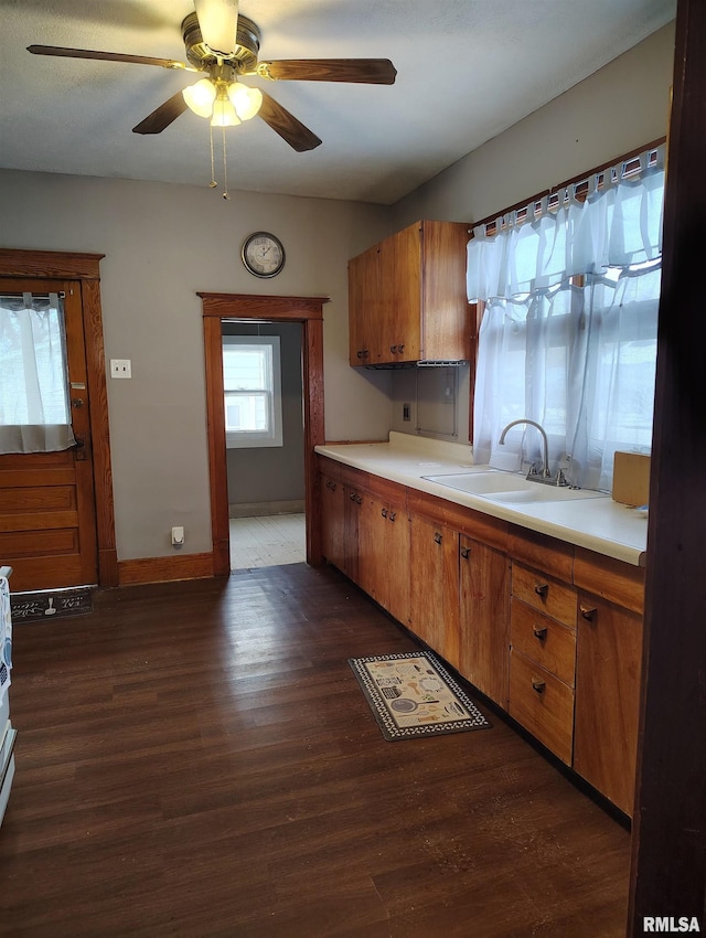 kitchen featuring light countertops, dark wood-style floors, brown cabinets, and a sink