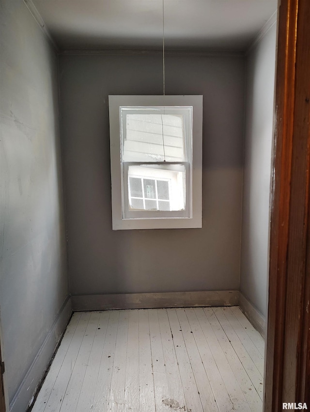 empty room featuring baseboards, light wood-style floors, and crown molding