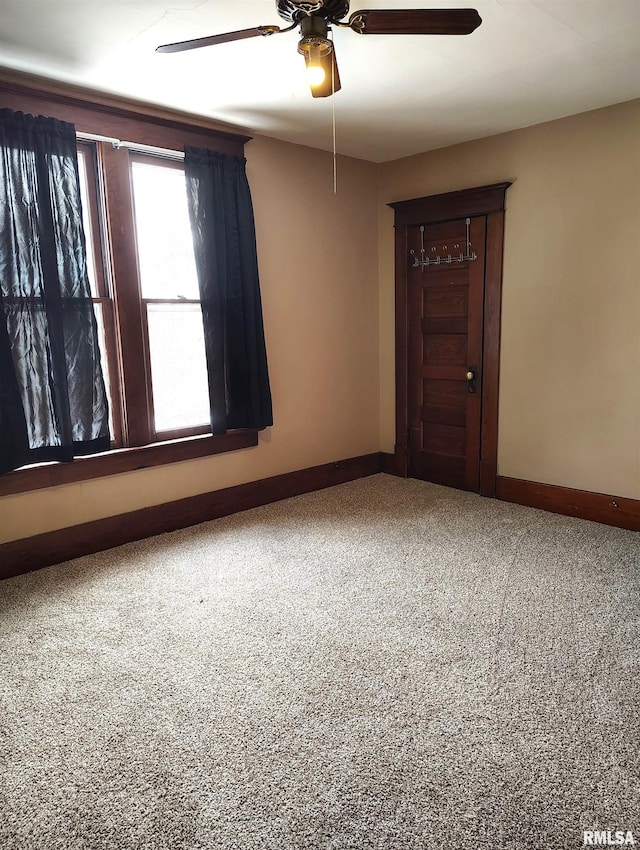 carpeted empty room with baseboards and a ceiling fan