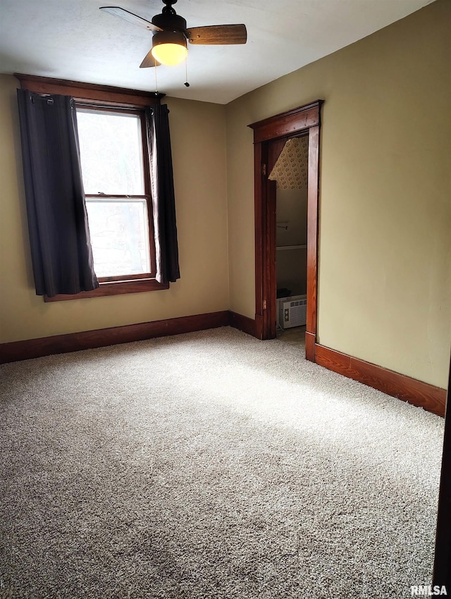 spare room featuring baseboards, a ceiling fan, an AC wall unit, and carpet flooring