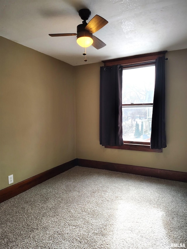 empty room featuring ceiling fan, speckled floor, and baseboards