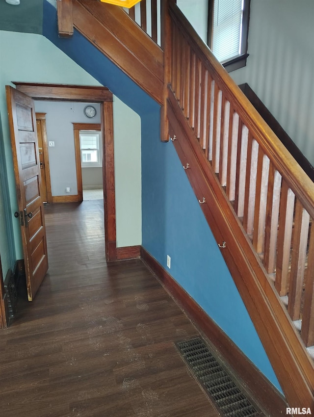 hallway featuring visible vents, stairway, dark wood-type flooring, and baseboards