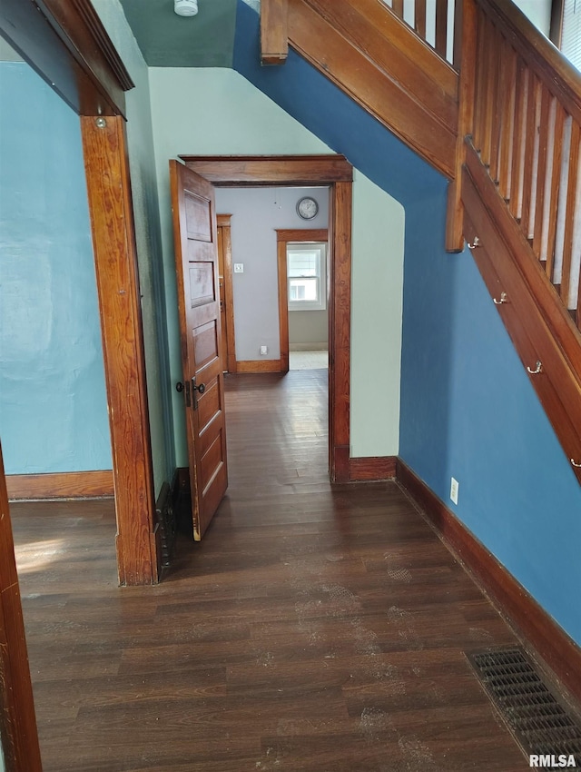 hallway featuring dark wood-style floors, visible vents, and baseboards