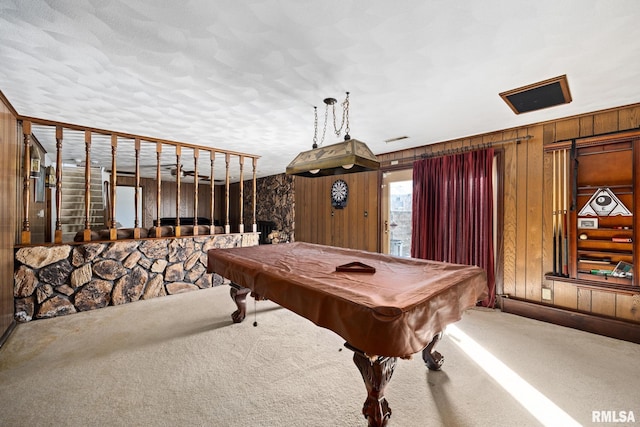 game room featuring pool table, a textured ceiling, wooden walls, and carpet flooring