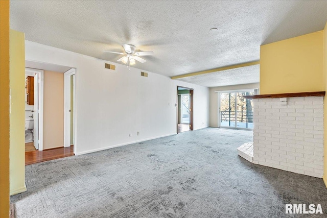 unfurnished living room with a brick fireplace, a textured ceiling, ceiling fan, and carpet