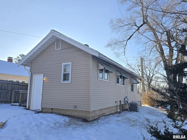 snow covered rear of property featuring cooling unit