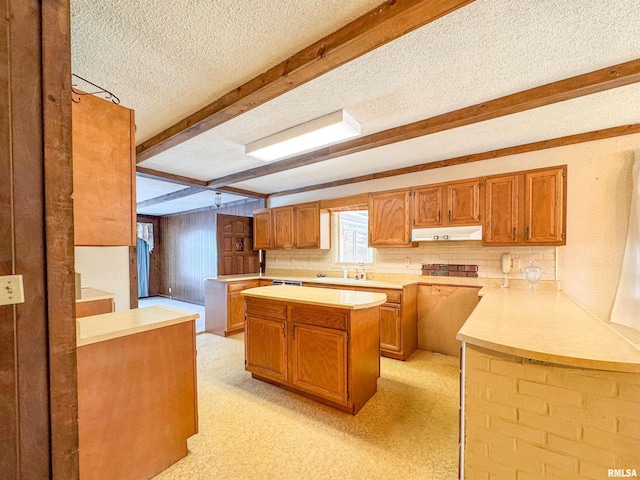 kitchen with sink, a center island, a textured ceiling, beamed ceiling, and kitchen peninsula