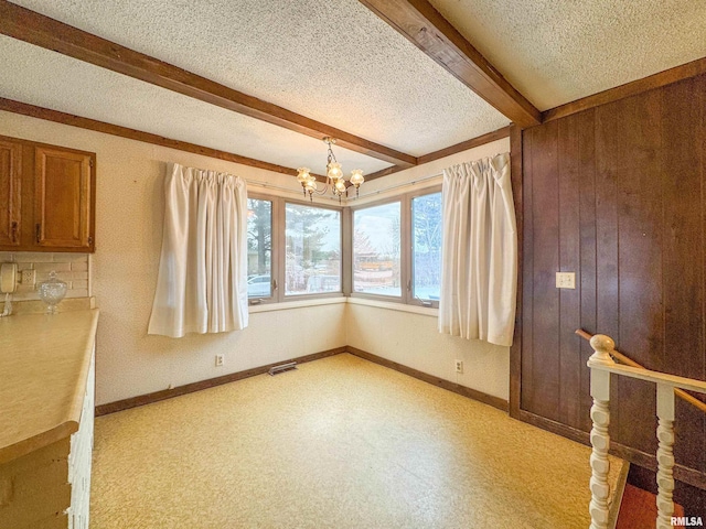 interior space with beamed ceiling, a textured ceiling, and a chandelier