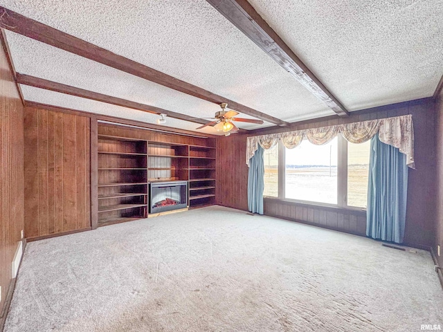 unfurnished living room with wood walls, a textured ceiling, beamed ceiling, and a water view