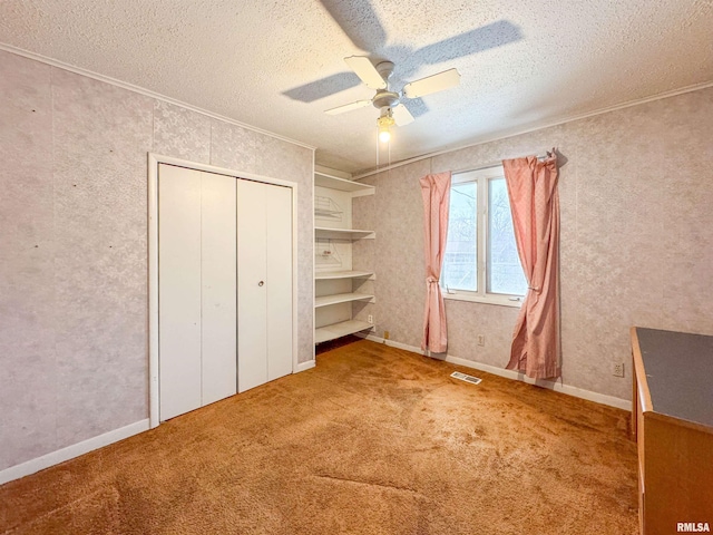 unfurnished bedroom with ceiling fan, a closet, a textured ceiling, and carpet flooring