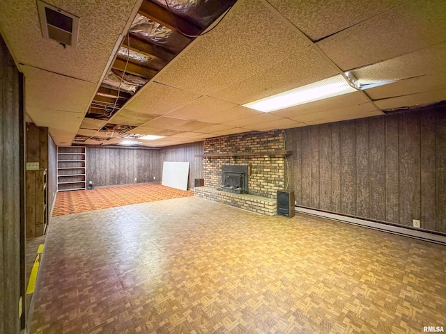 basement with wooden walls, baseboard heating, and parquet flooring