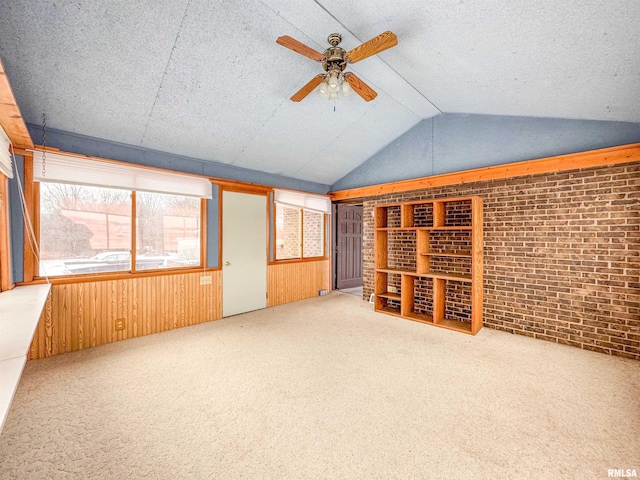 interior space featuring brick wall, light carpet, ceiling fan, and vaulted ceiling