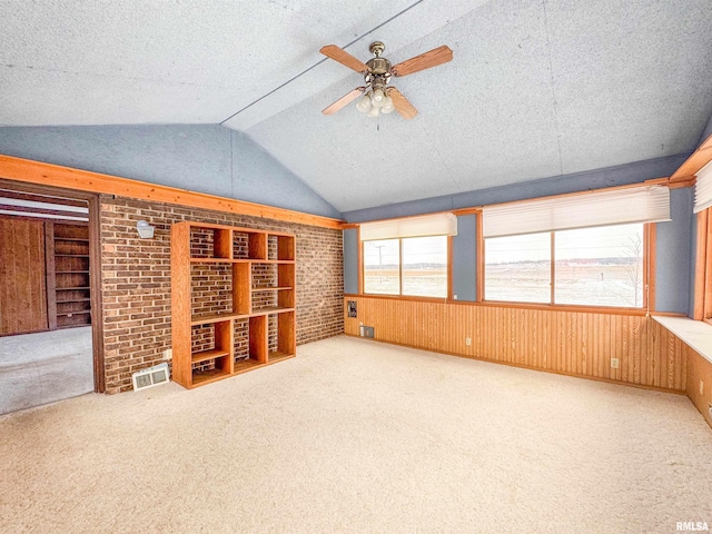 interior space with a textured ceiling, vaulted ceiling, carpet, ceiling fan, and built in shelves