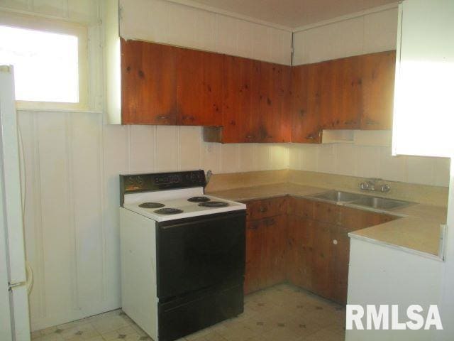 kitchen with white refrigerator, electric range, and sink