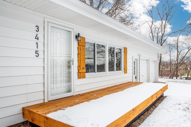 snow covered property entrance with a garage