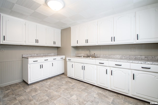 kitchen featuring sink, white cabinets, and wooden walls