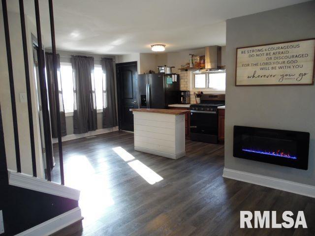 kitchen featuring a center island, stove, dark hardwood / wood-style floors, stainless steel refrigerator with ice dispenser, and ventilation hood