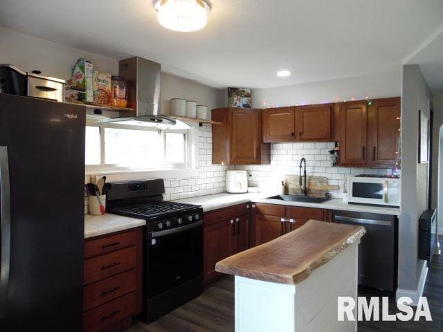 kitchen featuring sink, decorative backsplash, wall chimney range hood, black appliances, and dark wood-type flooring