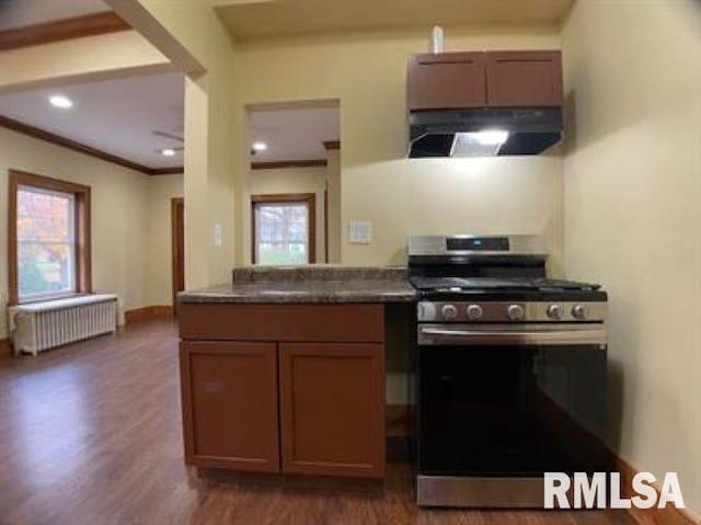 kitchen featuring dark hardwood / wood-style floors, extractor fan, stainless steel range with gas stovetop, crown molding, and radiator heating unit