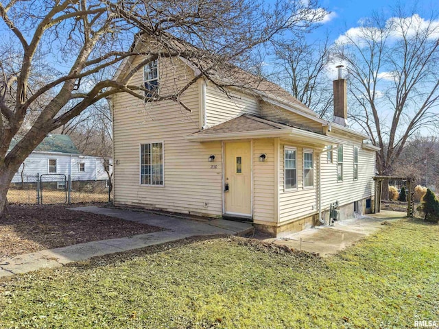 exterior space with a front yard, a gate, fence, and a chimney