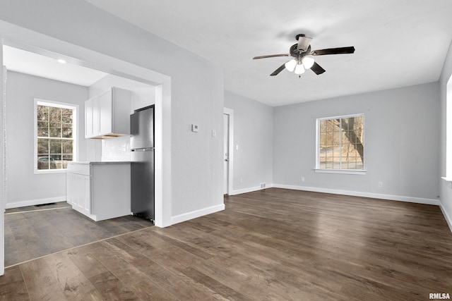 unfurnished living room with ceiling fan and dark hardwood / wood-style flooring