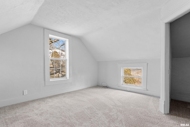 bonus room with carpet flooring, vaulted ceiling, and a textured ceiling