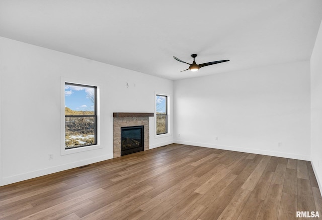 unfurnished living room featuring wood-type flooring, a healthy amount of sunlight, and ceiling fan