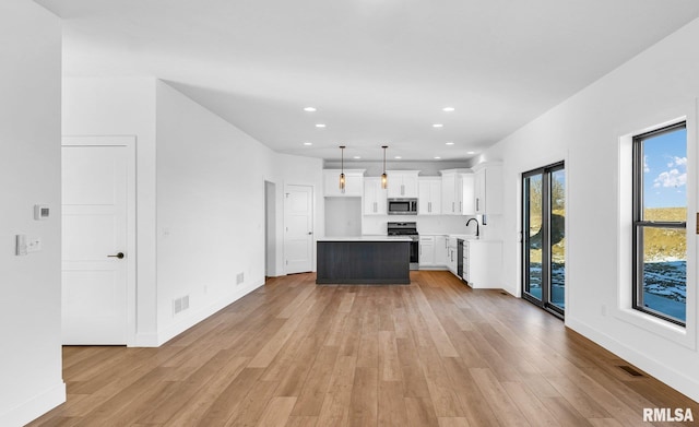 kitchen with pendant lighting, sink, white cabinets, a center island, and stainless steel appliances