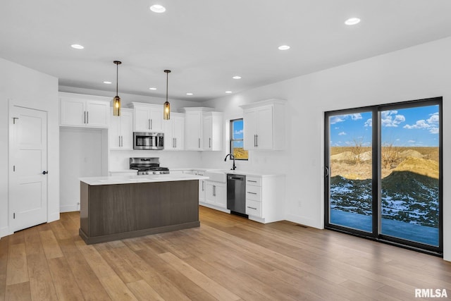 kitchen with white cabinetry, stainless steel appliances, decorative light fixtures, and a center island